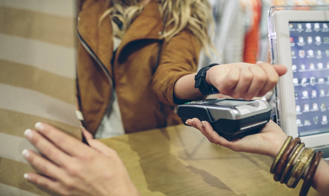 Spain, Asturias, Close up of unrecognizable blonde woman paying using smart watch with NFC technology in a store